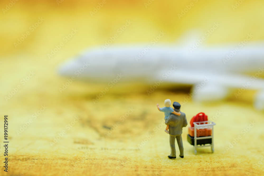 Family Travel Concept. Father and child miniature figures standing with airport trolley and baggages and mini airplane toy model on world map