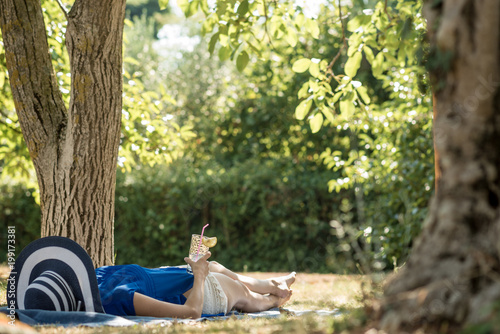 Woman lying relaxing in the shade of a tree in a  garden photo