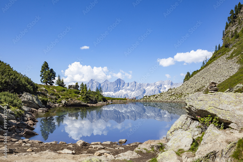 Mirror reflectons of mountain range Dachstein in lake Spiegelsee Mittersee