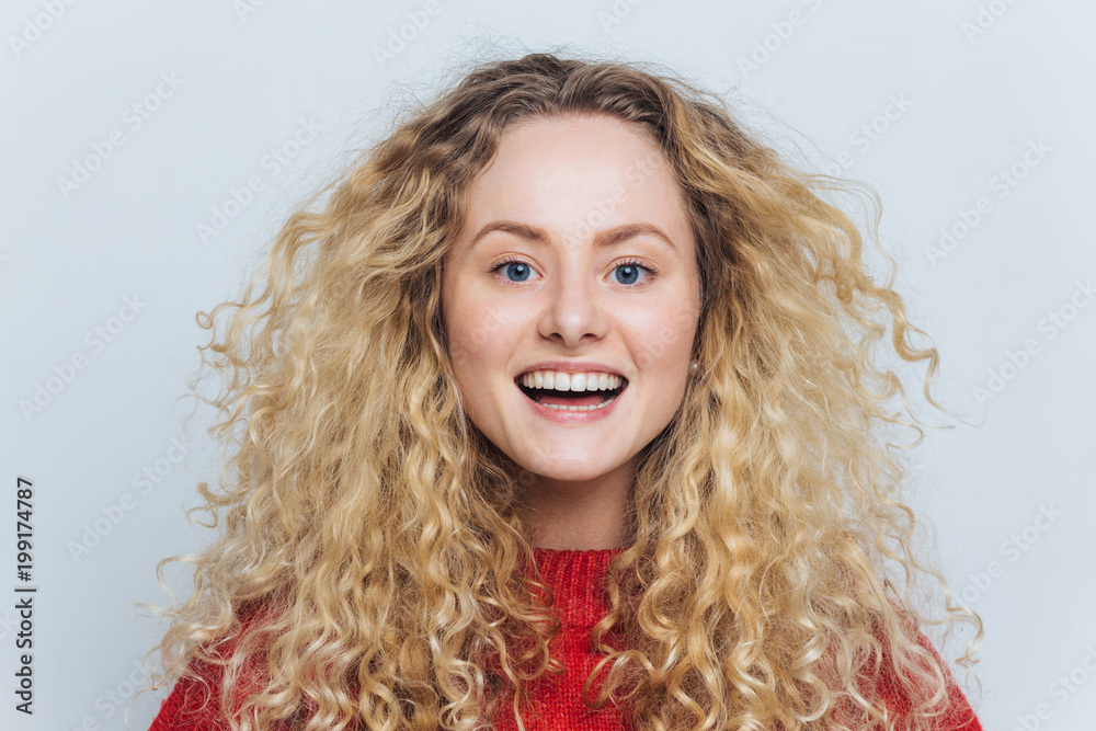 Horizontal portrait of happy adorable glad female with appealing look, feels excited as hears funny interesting story, isolated over white background. Smiling delighted woman with curly hairstyle Horizontal portrait of happy adorable glad female with appealing look, feels excited as hears funny interesting story, isolated over white background. Smiling delighted woman with curly hairstyle