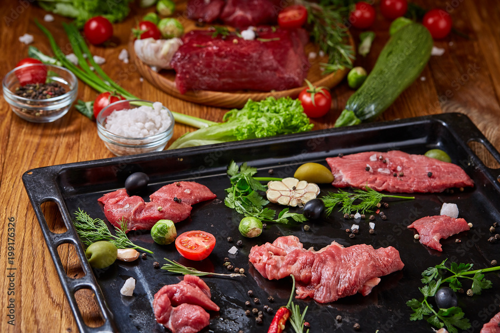 Still life of raw beef meat with vegetables on wooden plate, cooking tray over rustic background, selective focus Still life of raw beef meat with vegetables on wooden plate, cooking tray over rustic background, selective focus