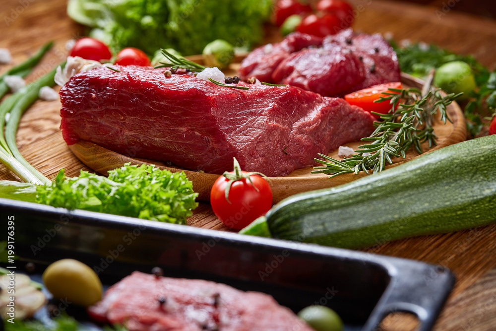 Still life of raw beef meat with vegetables on wooden plate, cooking tray over rustic background, selective focus Still life of raw beef meat with vegetables on wooden plate, cooking tray over rustic background, selective focus