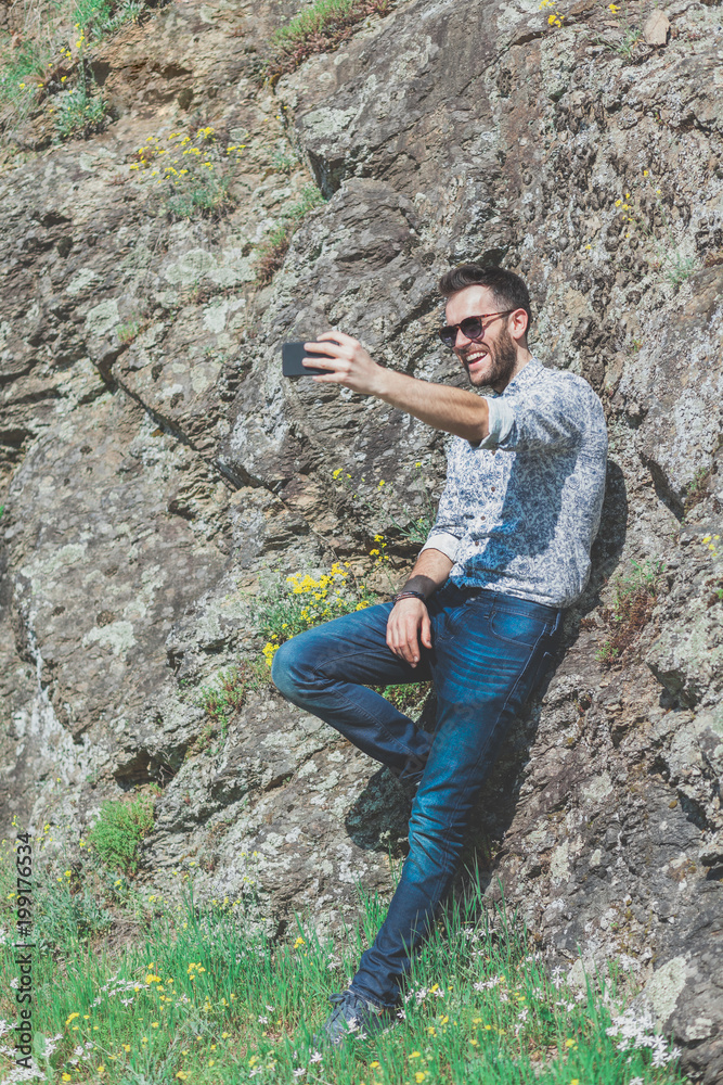 Naklejka premium Beautiful young man using smartphone in the nature