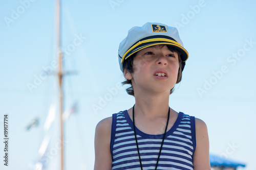 Portrait of a boy in a striped T-shirt and captain's cap. © Sergey Kohl
