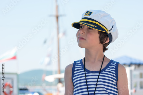 Portrait of a boy in a striped T-shirt and captain's cap. © Sergey Kohl