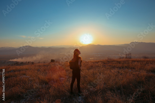 Sunset mountain. Tourist Free happy woman outstretched arms with backpack enjoying life in wheat field. Hiker cheering elated and blissful with arms raised.