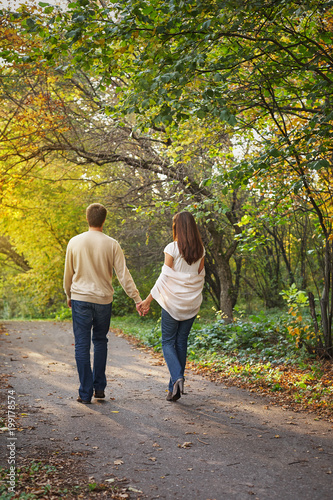 Young romantic couple in love walking in the autumn park holding hands. Lifestyle concept