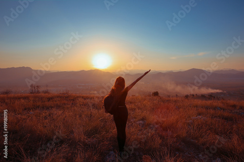 Sunset mountain. Tourist Free happy woman outstretched arms with backpack enjoying life in wheat field. Hiker cheering elated and blissful with arms raised.