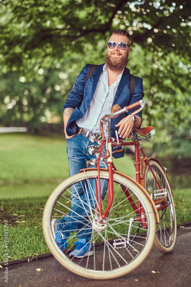 Obraz premium Traveler dressed in casual clothes and sunglasses with a backpack, relaxing in a city park after riding on a retro bicycle.