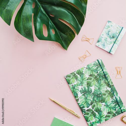 Monstera leaf, notebook, pen, scissors made with tropical palm style on pink background. Flat lay, top view minimal  concept.