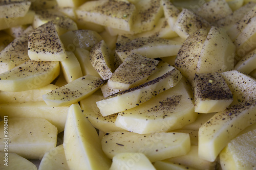 Raw potatoes sliced for cooking French fries in a rustic manner.