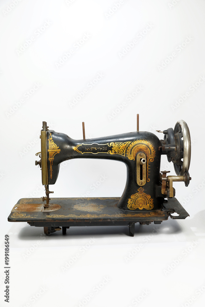 An old antique sewing machine, decorated with golden ornaments. Vertical frame.