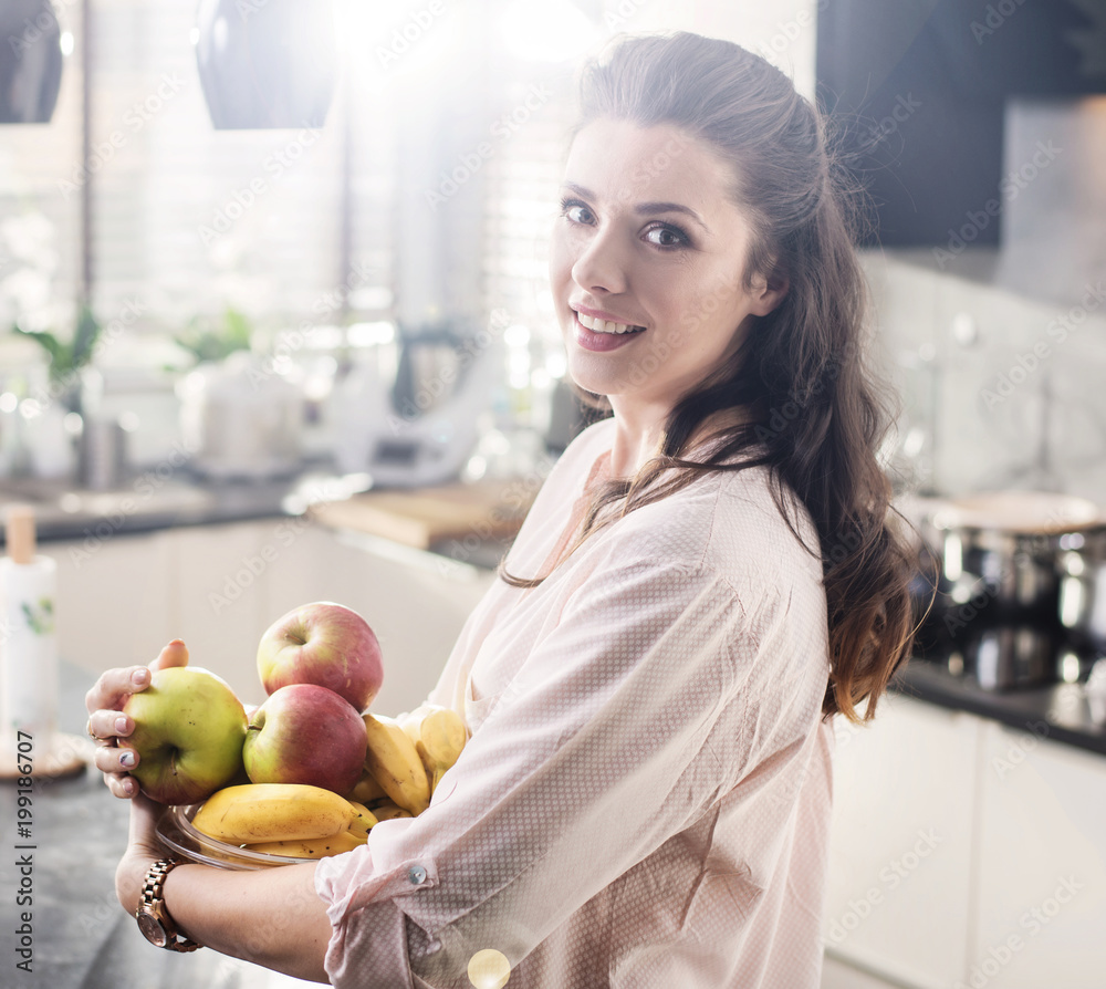 Cheerful woman holding a bowl full of fruit Cheerful woman holding a bowl full of fruit