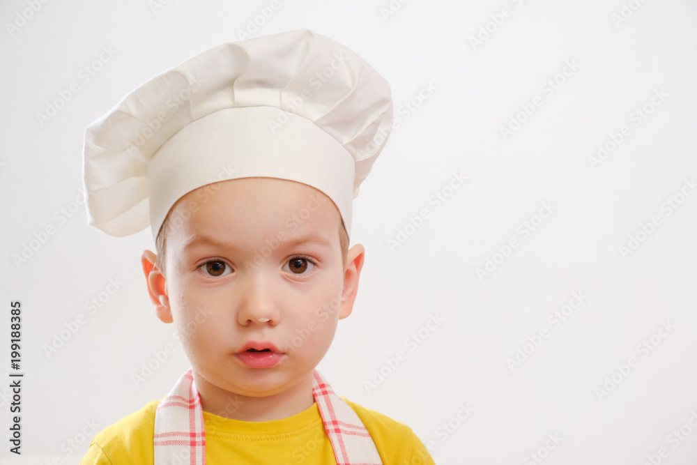 Portrait of a child in a cook cap and an apron on a white background Portrait of a child in a cook cap and an apron on a white background