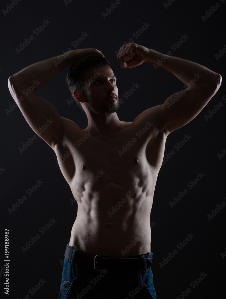 young man hands up on black background low key photo young man hands up on black background low key photo