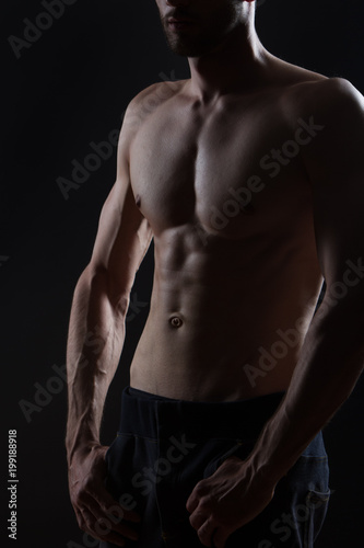 young man body with muscles on black background
