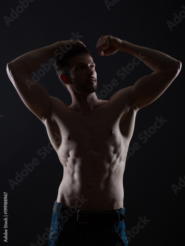 young man hands up on black background low key photo