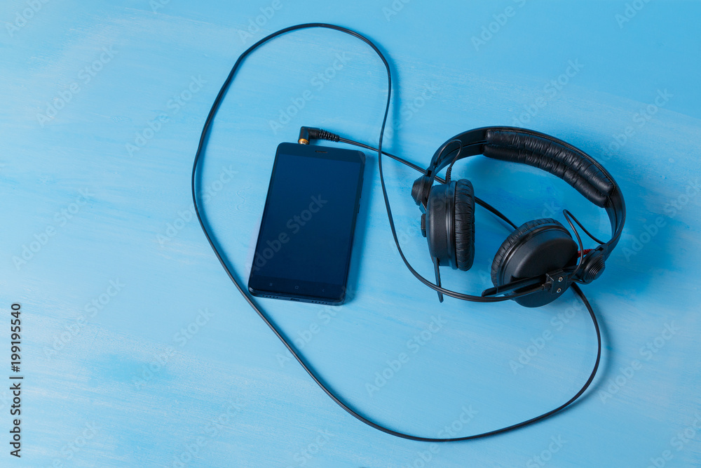 Smartphone with DJ headphones on blue background