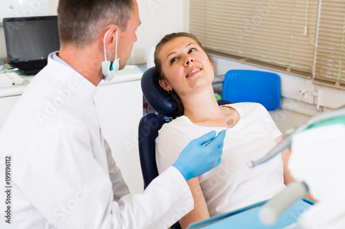 Dentist in uniform is taking examination of a young female