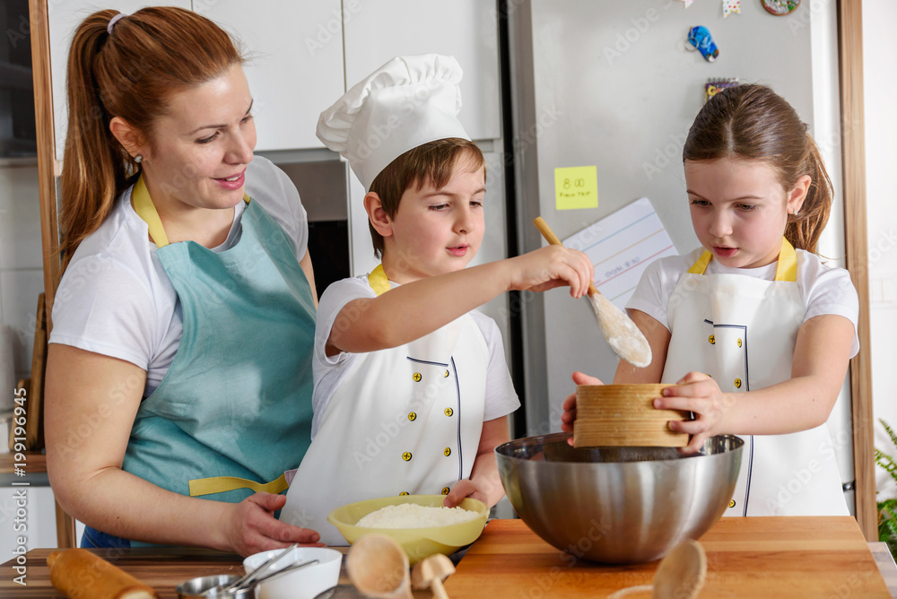 Children helping mother in the kitchen baking together. Home activities with kids. Children helping mother in the kitchen baking together. Home activities with kids.