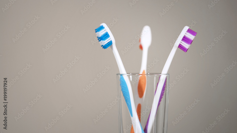Three colored toothbrushes stand on shelf in bathroom, care for oral cavity Three colored toothbrushes stand on shelf in bathroom, care for oral cavity