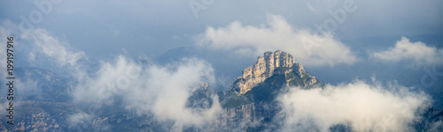 Mountaintops covered with clouds during sunrise panorama, a rocky top at Puertos de Beceite national Parc in between of clouds