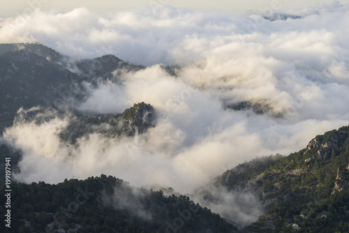 Aerial view on mountaintops covered with clouds during sunrise