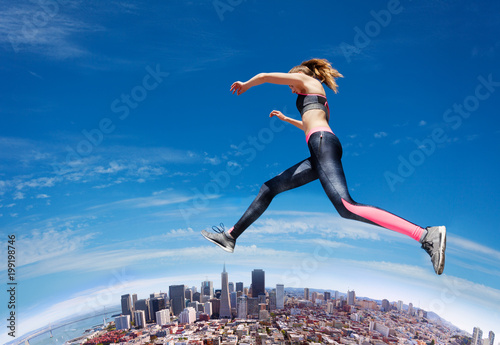 Jumping fit girl across blue sky