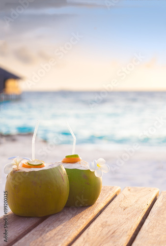 two fresh coconut cocktails on a tropical beach. evening