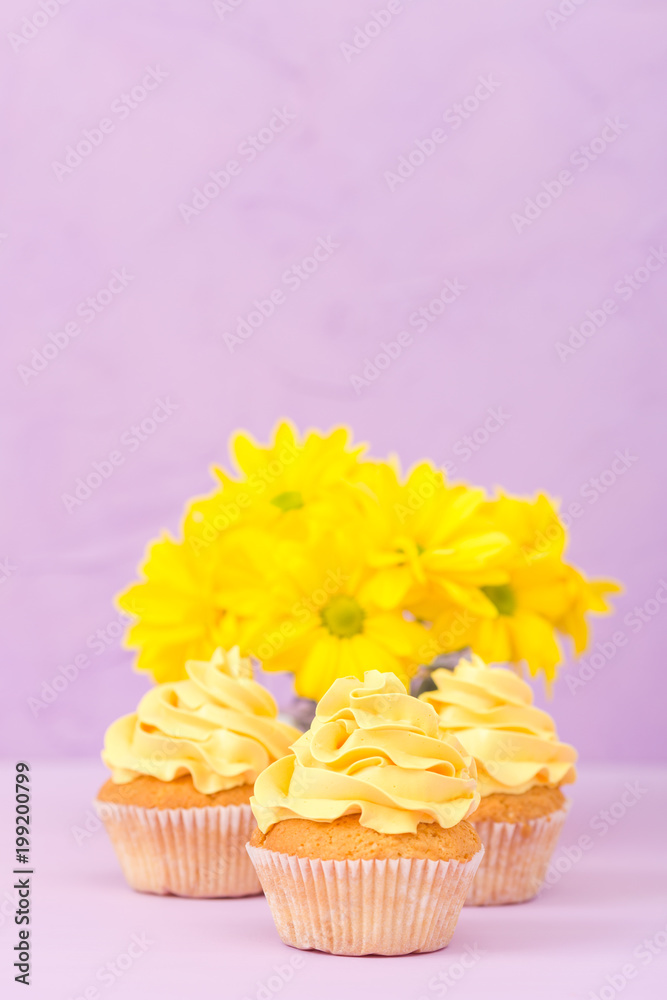 Cupcakes decorated with yellow cream and chrysanthemums on violet pastel background for greeting card with copyscape. Cupcakes decorated with yellow cream and chrysanthemums on violet pastel background for greeting card with copyscape.