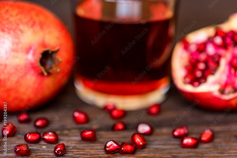 Ripe pomegranates with glass of juice on table Ripe pomegranates with glass of juice on table
