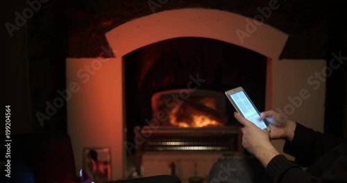 Bearded man uses a tablet near the fireplace sliding photo