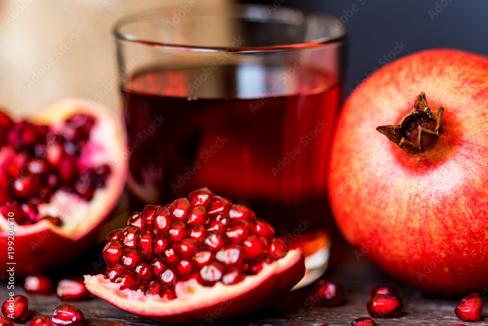 Ripe pomegranates with glass of juice on table Ripe pomegranates with glass of juice on table