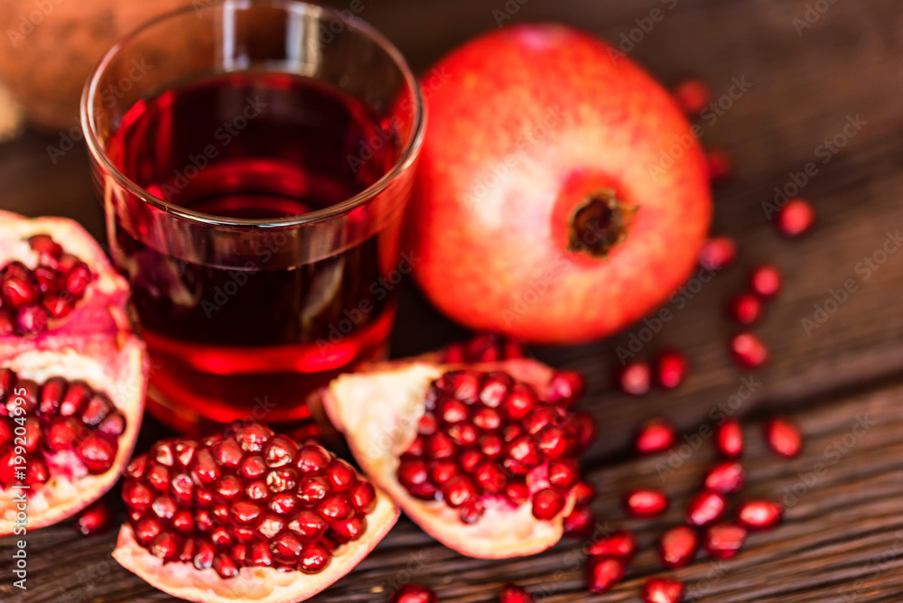 Ripe pomegranates with glass of juice on table Ripe pomegranates with glass of juice on table