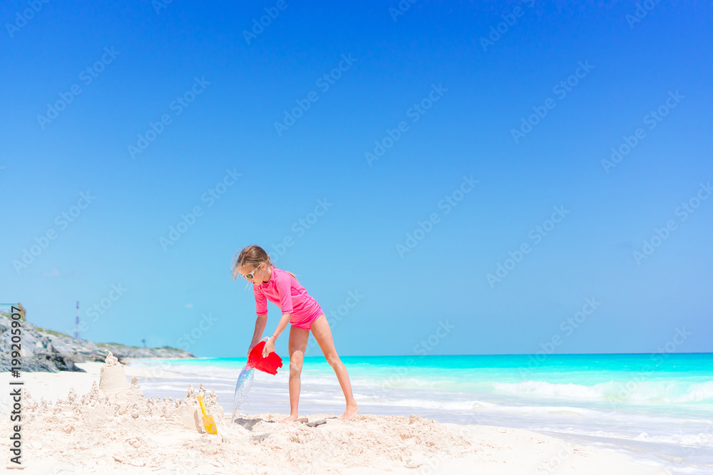 Adorable little girl playing with beach toys on white tropial beach Adorable little girl playing with beach toys on white tropial beach