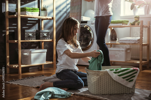 Daughter helping mother at laundry room