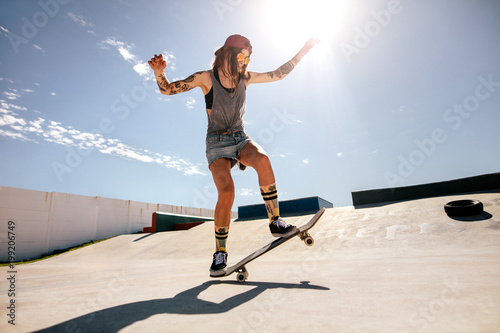 Female skater skateboarding at skate park.