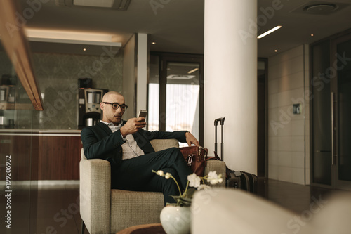 Business traveler waiting in airport lounge using phone photo