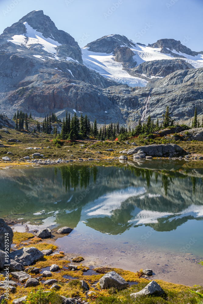Face Mountain, glaciers and conifer tree reflections, Semaphore Lakes, Canada.