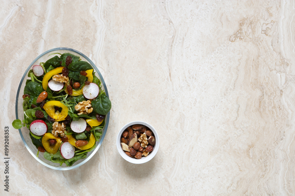 Healthy vegan salad with radish, nuts, yellow pepper on marble with copy space to right Healthy vegan salad with radish, nuts, yellow pepper on marble with copy space to right