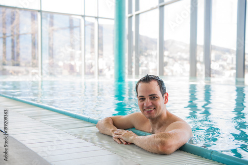 Handsome man relaxing in a indoor swimming pool