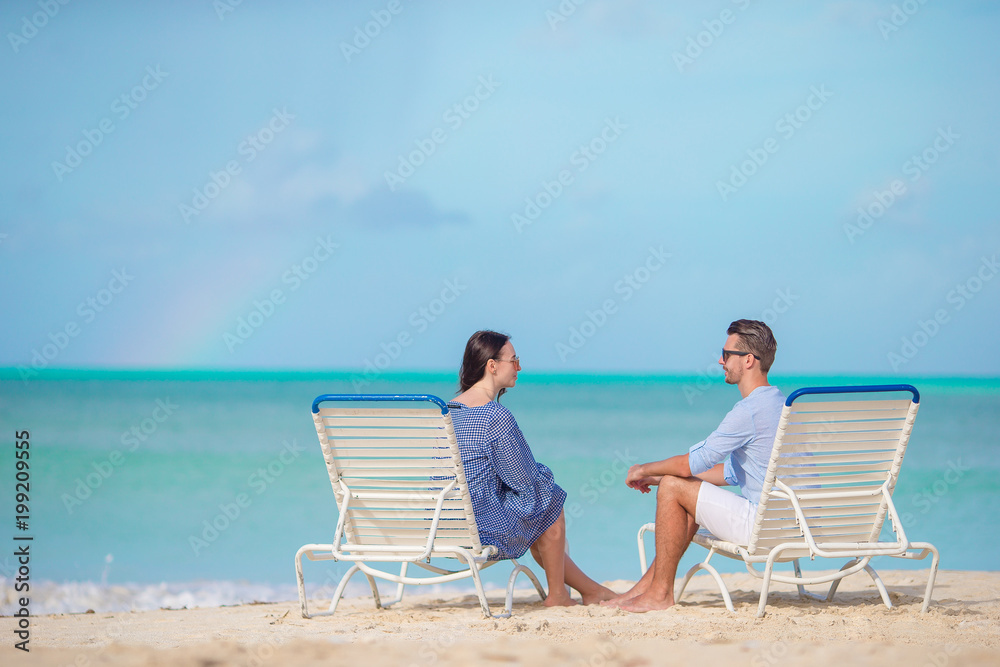 Young couple on white beach during summer vacation. Happy family enjoy their honeymoon