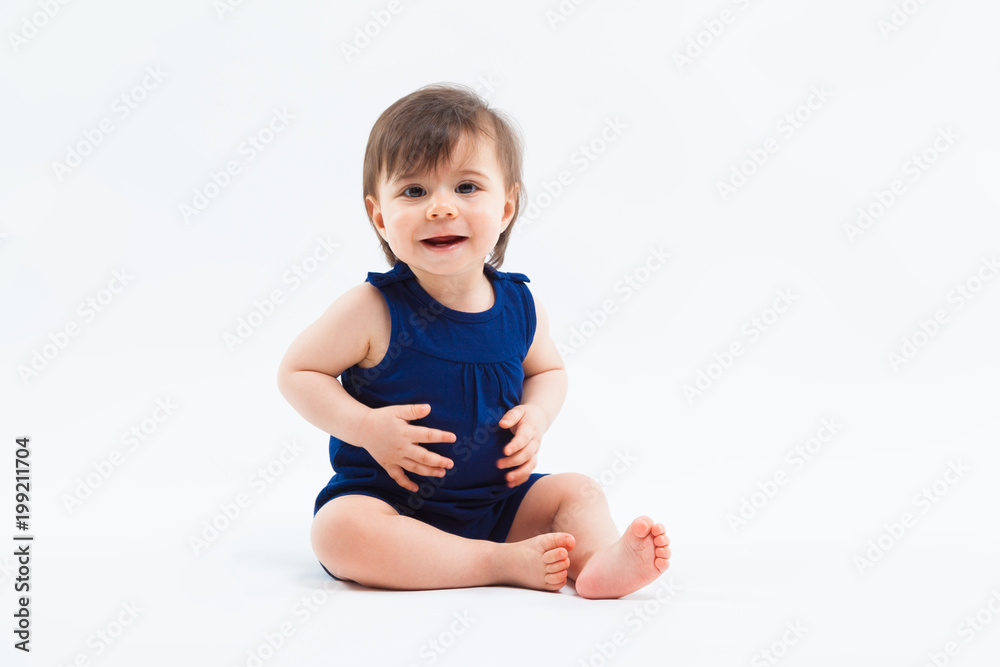 Cute funny small smiling girl sitting in studio posing on white background Cute funny small smiling girl sitting in studio posing on white background