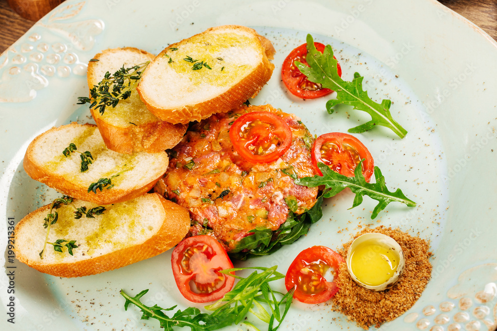 Beef tartare with egg yolk and tomato on table