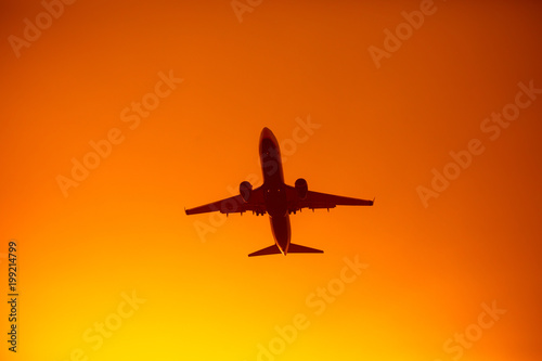 flying airplane silhouette in the orange sky sunset