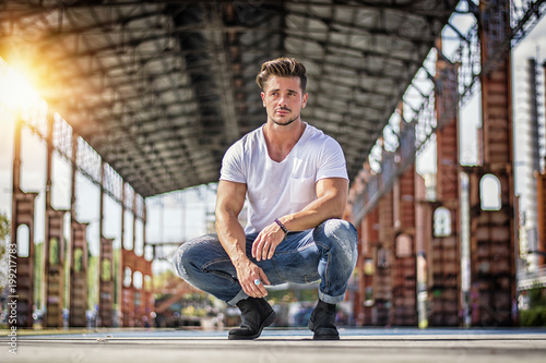 Attractive man in urban setting under big metal structure, a former industrial site