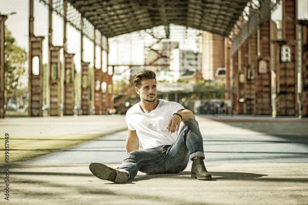 Attractive man in urban setting under big metal structure, a former industrial site Attractive man in urban setting under big metal structure, a former industrial site