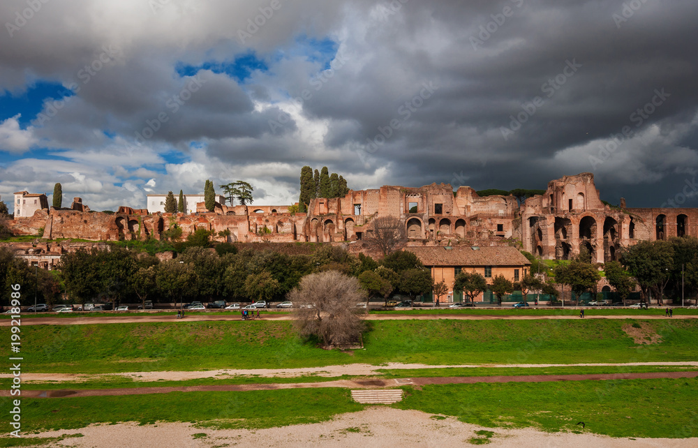 Panoramic view of the Ancient Rome Imperial Palace ruins on Palatine Hill with stormy clouds from Circuss Maximus, in the historic center of Rome