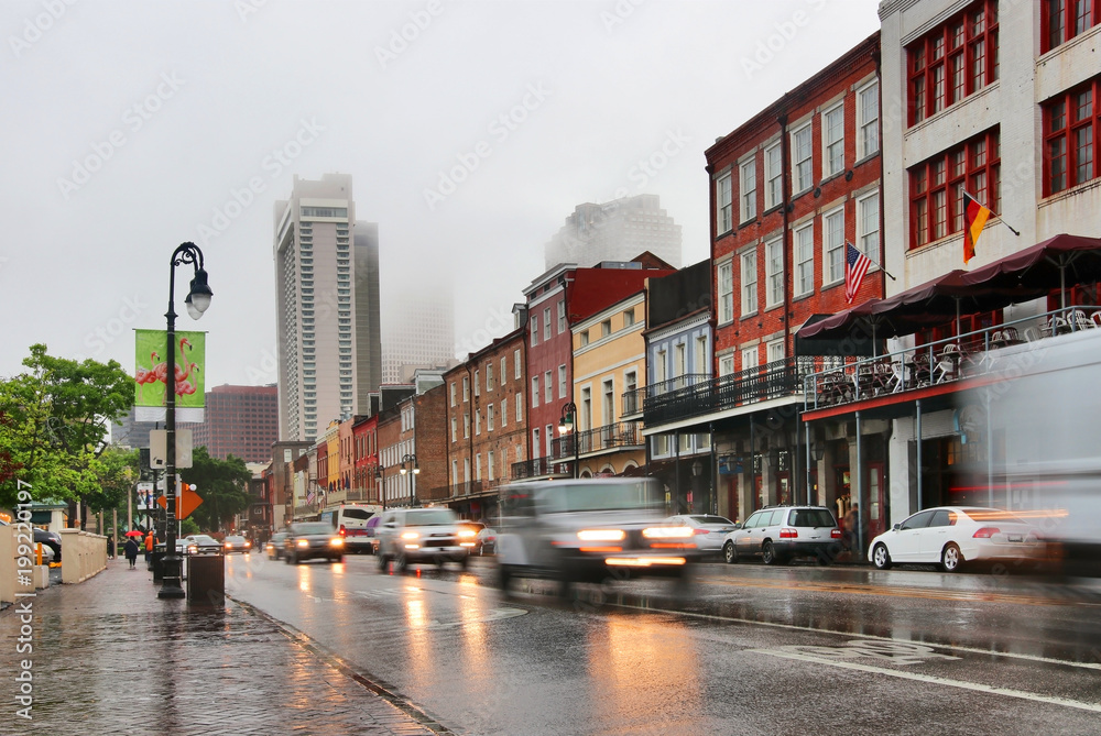 New Orleans cityscape during rainy day. Street view with French Quarter, Downtown buildings in a fog and cars in a motion on a wet road. Spring rain in New Orleans, Louisiana, USA.