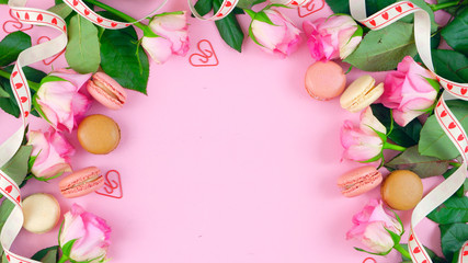 Happy Mother's Day background of pink roses and macaron cookies on pink wood table with copy space.